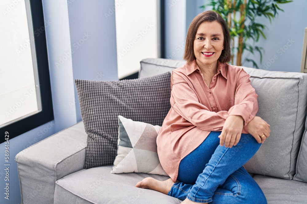 Middle age woman smiling confident sitting on sofa at home Middle age woman smiling confident sitting on sofa at home