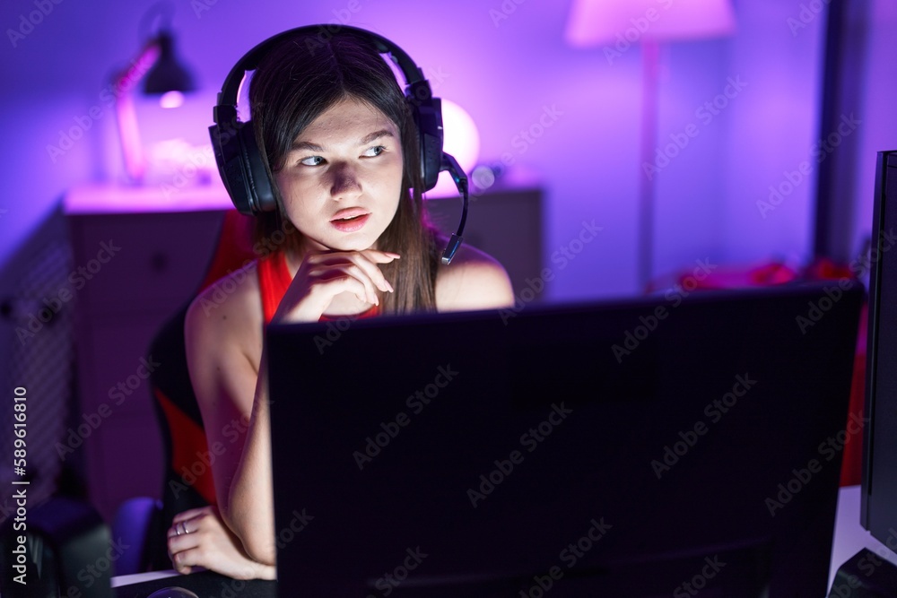Young caucasian woman streamer sitting on table with serious expression at gaming room Young caucasian woman streamer sitting on table with serious expression at gaming room