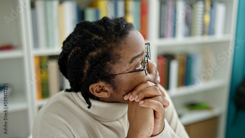 African american woman student sitting with doubt expression at library university