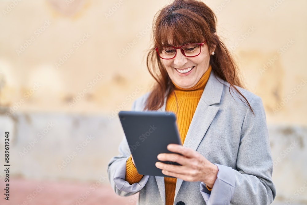 Fototapeta premium Middle age woman business executive using touchpad at street
