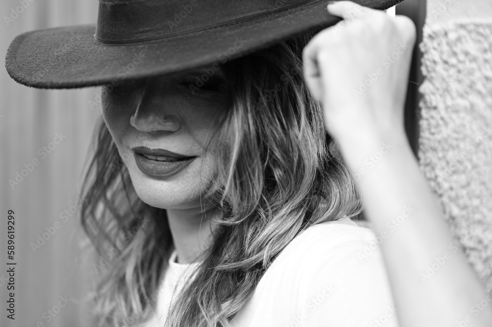 Beautiful young mysterious blonde girl in black hat and black jacket on gray background. beautiful eyes and hair with a hat. She manicures long red nails, nail polish. Fashion, beauty. Beautiful young mysterious blonde girl in black hat and black jacket on gray background. beautiful eyes and hair with a hat. She manicures long red nails, nail polish. Fashion, beauty.