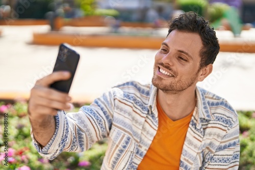 Young hispanic man smiling confident making selfie by the smartphone at park