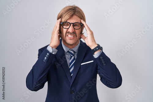Caucasian man with mustache wearing business clothes with hand on head, headache because stress. suffering migraine.