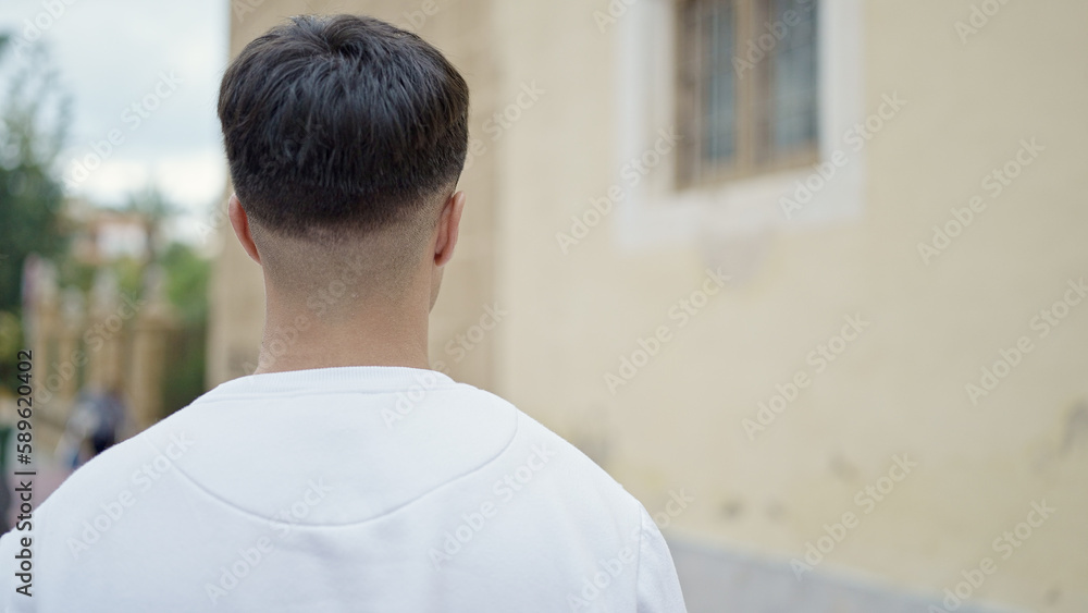 Young hispanic man standing backwards at street Young hispanic man standing backwards at street