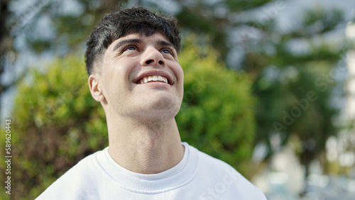 Young hispanic man smiling confident looking to the sky at park