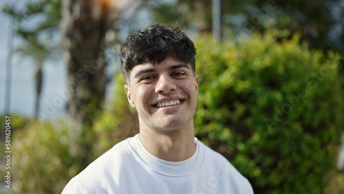 Young hispanic man smiling confident standing at park
