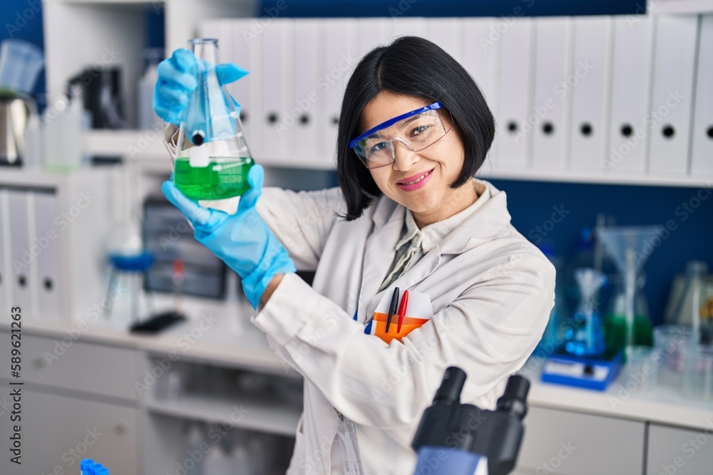 Young chinese woman scientist measuring liquid at laboratory Young chinese woman scientist measuring liquid at laboratory