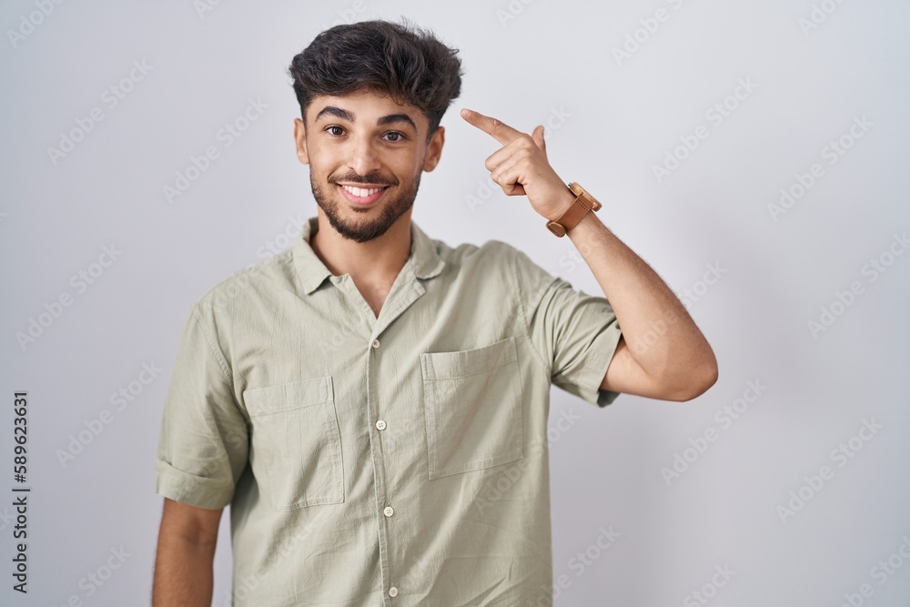 Arab man with beard standing over white background smiling pointing to head with one finger, great idea or thought, good memory Arab man with beard standing over white background smiling pointing to head with one finger, great idea or thought, good memory