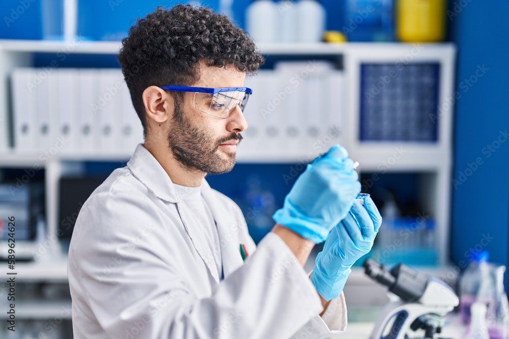 Young arab man wearing scientist uniform holding pills at laboratory Young arab man wearing scientist uniform holding pills at laboratory