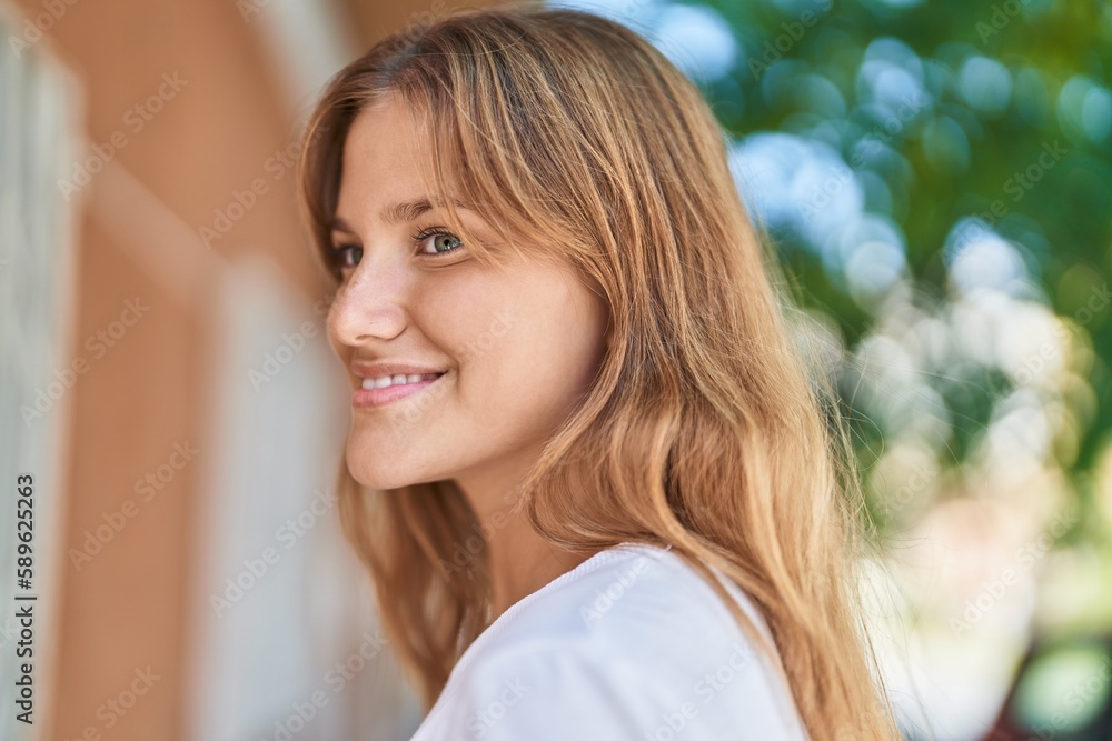 Young blonde girl smiling confident looking to the side at street