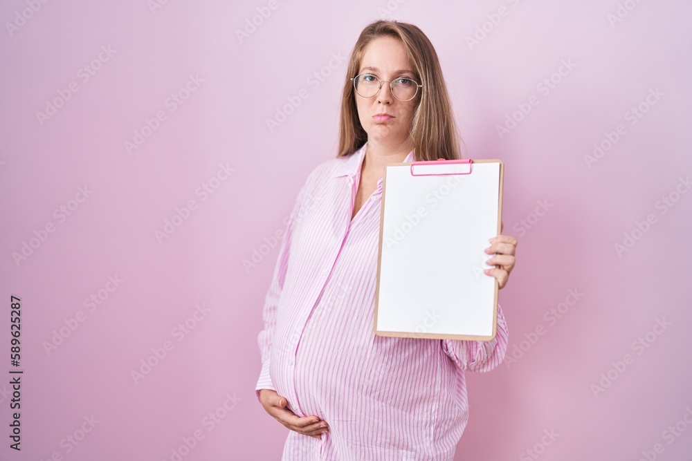 Young pregnant woman holding clipboard depressed and worry for distress, crying angry and afraid. sad expression. Young pregnant woman holding clipboard depressed and worry for distress, crying angry and afraid. sad expression.