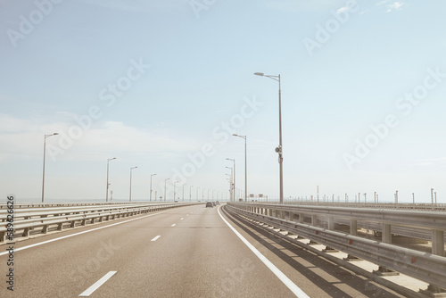 Automobile bridge across the Kerch Strait or Crimean bridge. Asphalt road with marking and road lampposts with alarm annunciators.