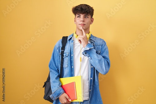 Obraz na plátně Hispanic teenager wearing student backpack and holding books thinking concentrat