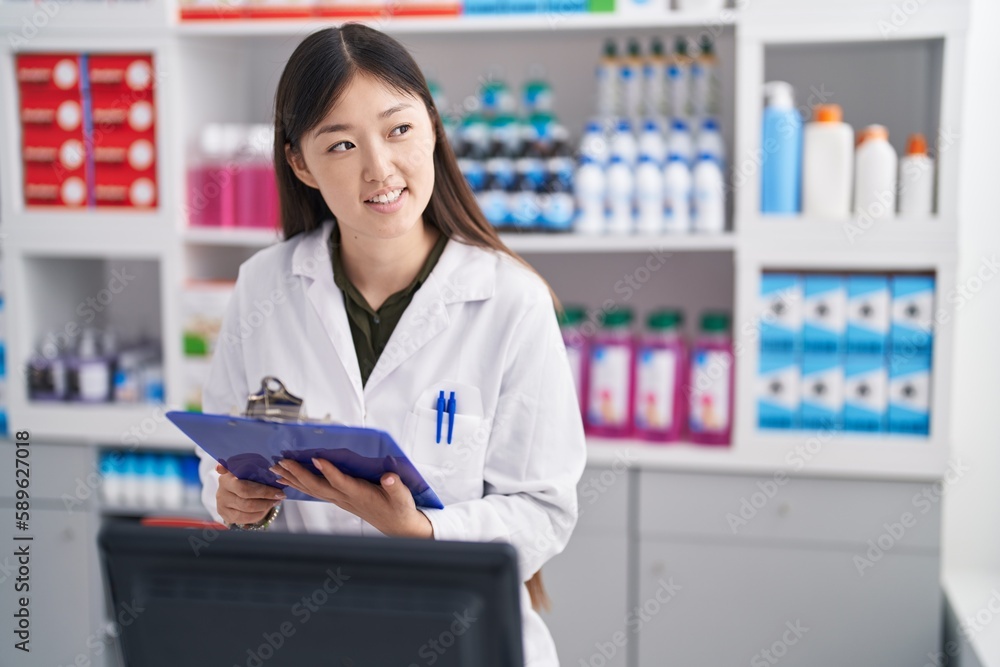 Chinese woman pharmacist writing on document at pharmacy