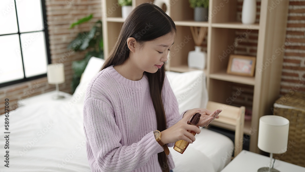 Young chinese woman having hair treatment sitting on bed at bedroom Young chinese woman having hair treatment sitting on bed at bedroom