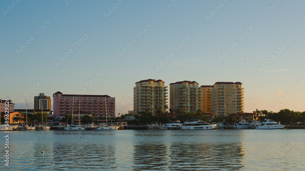 Fototapeta premium City Scape of water with tall buildings on a sunny day. A construction crane is in middle with a blue sky.