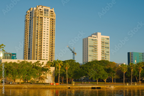 City Scape of water with tall buildings on a sunny day. A construction crane is in middle with a blue sky.