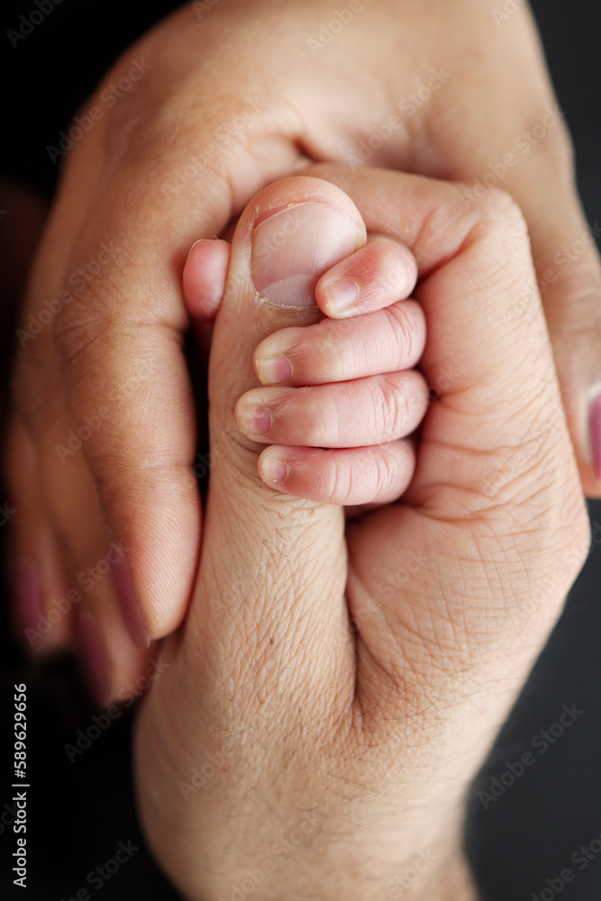 Close up little hand of child and palm of mother and father. The newborn baby has a firm grip on the parent's finger after birth. Parenting, childcare and healthcare concept. Professional macro photo - obrazy, fototapety, plakaty 