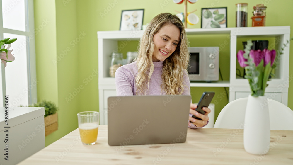Young blonde woman using laptop and smartphone at dinning room Young blonde woman using laptop and smartphone at dinning room