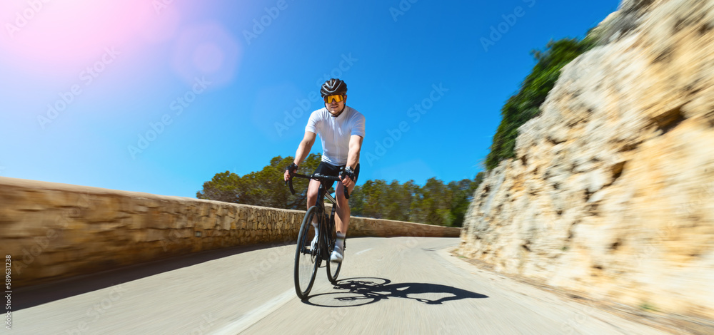 Man Adult on a racing bike climbing the hill at mediterranean sea landscape coastal road on mallorca balearic island