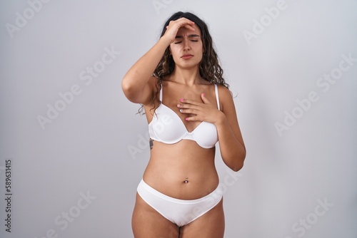 Young hispanic woman wearing white lingerie touching forehead for illness and fever, flu and cold, virus sick © Krakenimages.com