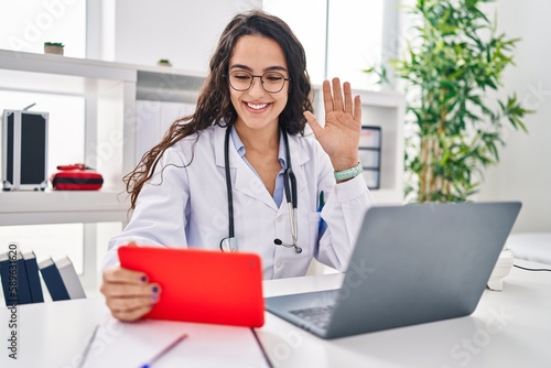 Young doctor woman working on online appointment looking positive and happy standing and smiling with a confident smile showing teeth