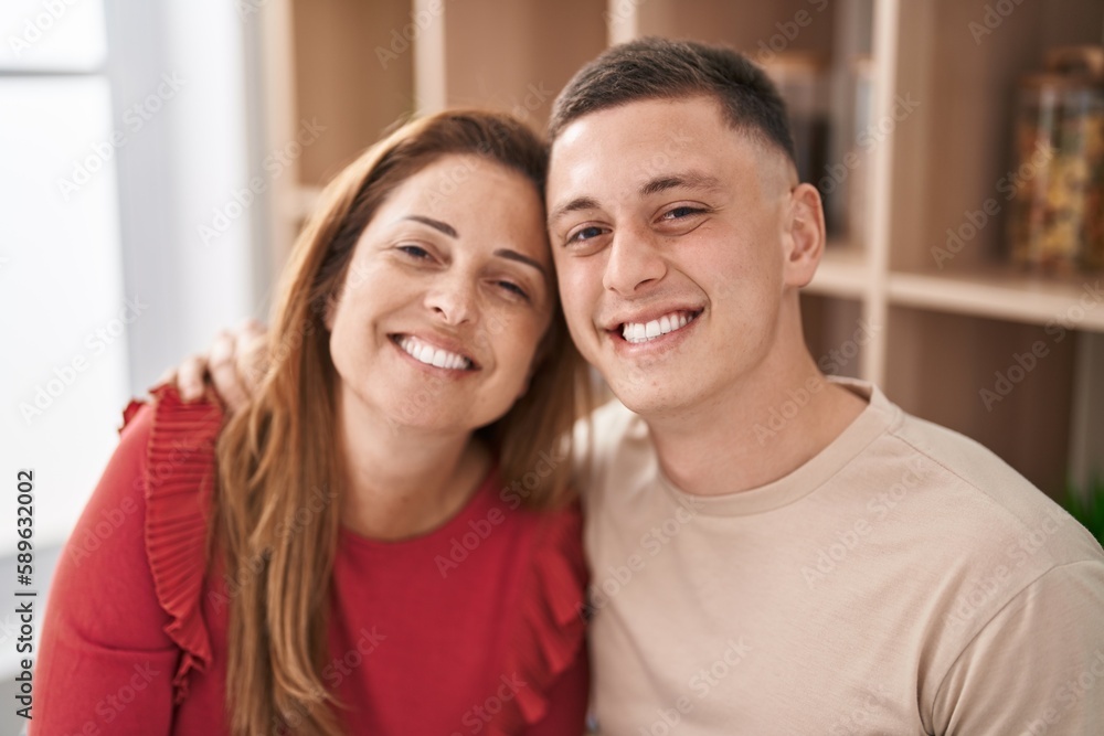 Man and woman mother and son hugging each other sitting on desk at home Man and woman mother and son hugging each other sitting on desk at home