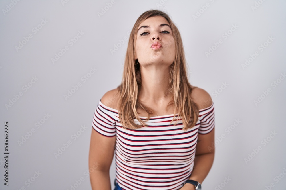 Young hispanic woman standing over isolated background looking at the camera blowing a kiss on air being lovely and sexy. love expression. Young hispanic woman standing over isolated background looking at the camera blowing a kiss on air being lovely and sexy. love expression.