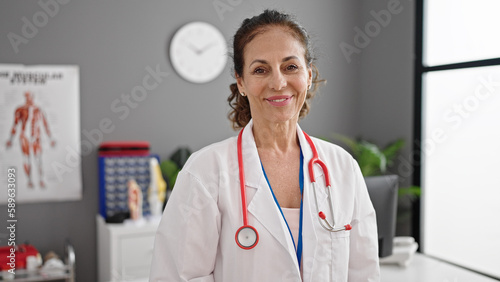 Middle age hispanic woman doctor smiling confident standing at clinic