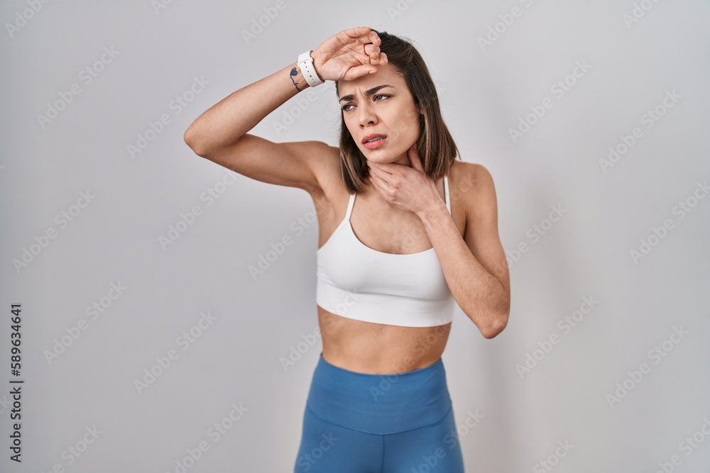 Hispanic woman wearing sportswear over isolated background touching forehead for illness and fever, flu and cold, virus sick Hispanic woman wearing sportswear over isolated background touching forehead for illness and fever, flu and cold, virus sick