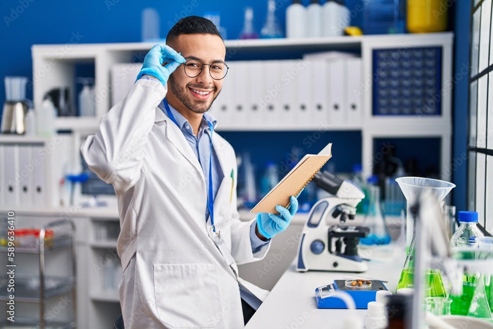 African american man scientist reading book working at laboratory African american man scientist reading book working at laboratory