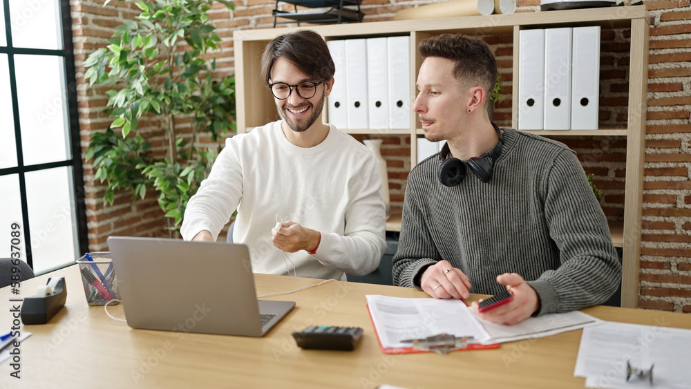 Two men business partners using laptop and smartphone working at office Two men business partners using laptop and smartphone working at office