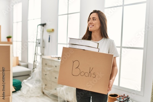 Young hispanic woman smiling confident holding books package at new home © Krakenimages.com