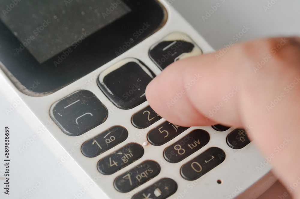 fingers or hands of someone who is holding an old GSM mobile phone on the keypad fingers or hands of someone who is holding an old GSM mobile phone on the keypad