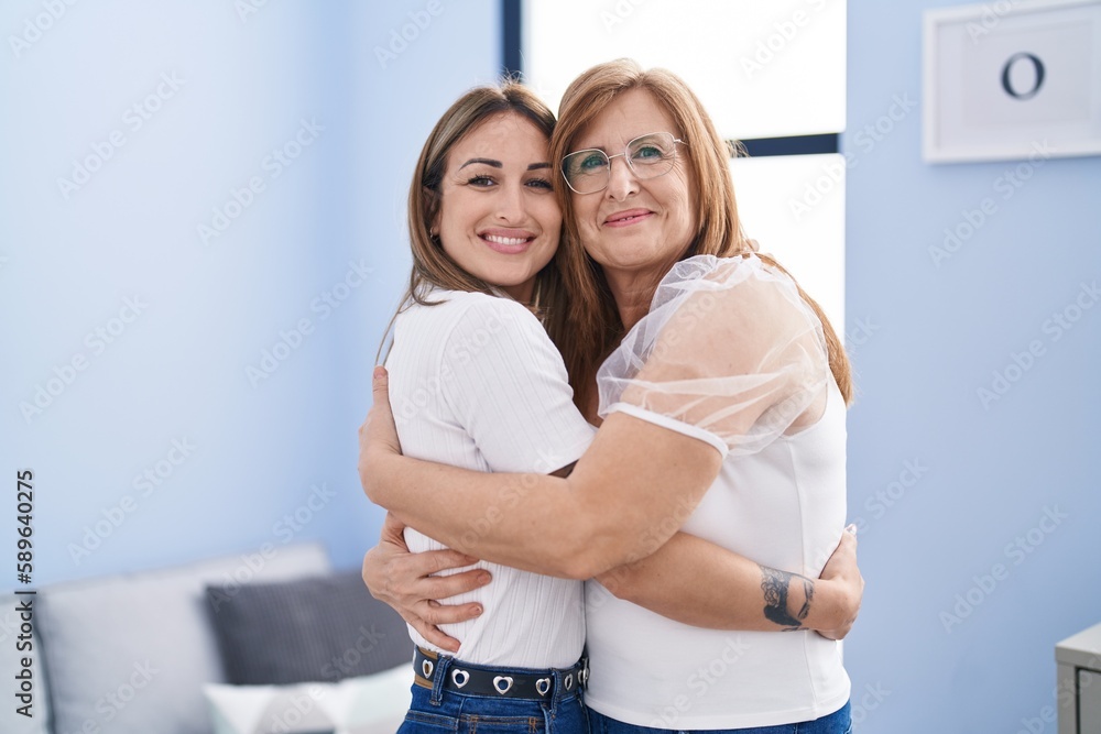 Mother and daughter hugging each other standing at home