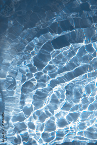 Abstract nature textured background, water waves in the pool with sun reflection. Clear water with bubbles and circles on blue background © Olha
