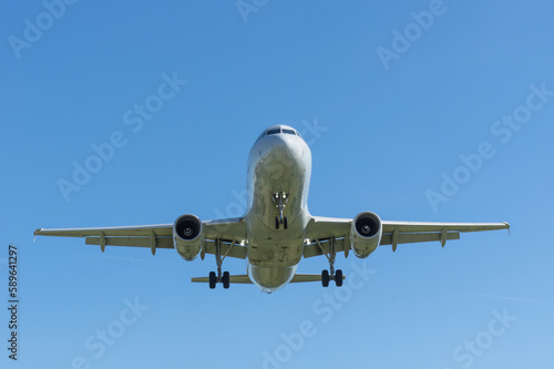 Modern passenger jet shown approaching for landing shown against a blue sky.