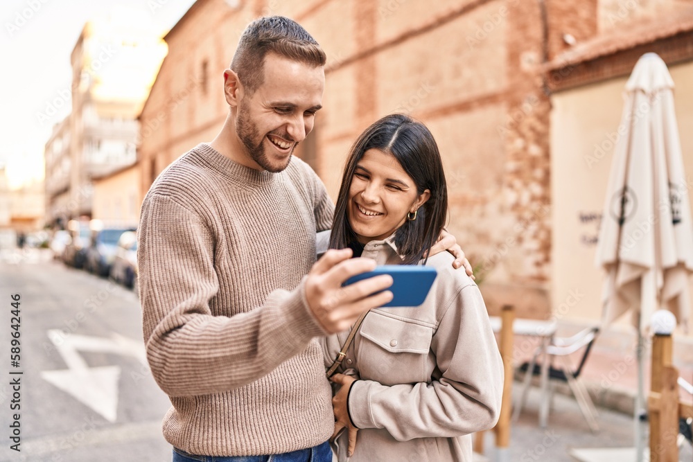 Man and woman couple smiling confident using smartphone at street Man and woman couple smiling confident using smartphone at street