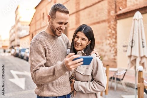 Man and woman couple smiling confident using smartphone at street