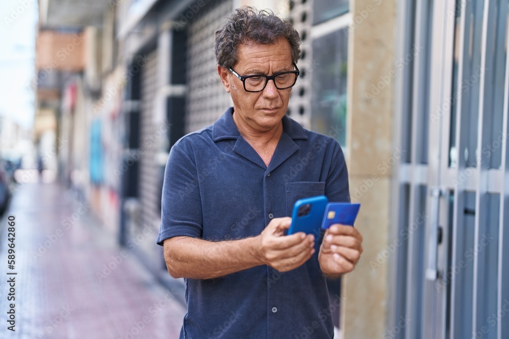 Middle age man using smartphone and credit card at street Middle age man using smartphone and credit card at street