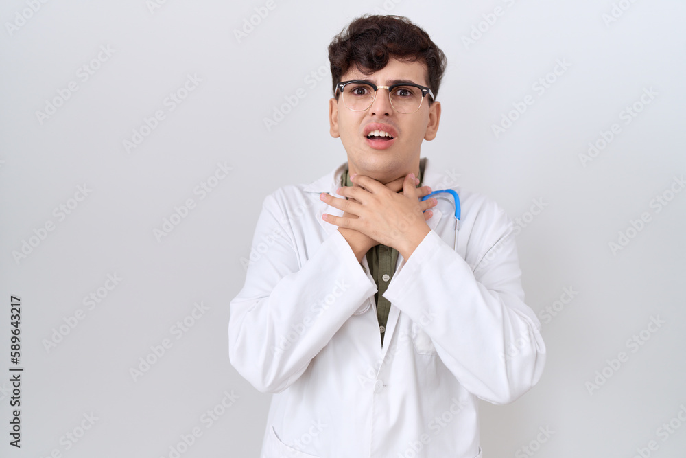 Young non binary man wearing doctor uniform and stethoscope shouting and suffocate because painful strangle. health problem. asphyxiate and suicide concept. Young non binary man wearing doctor uniform and stethoscope shouting and suffocate because painful strangle. health problem. asphyxiate and suicide concept.