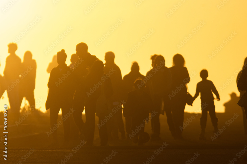 The silhouette of a crowd of people goes towards the yellow bright sunset The silhouette of a crowd of people goes towards the yellow bright sunset