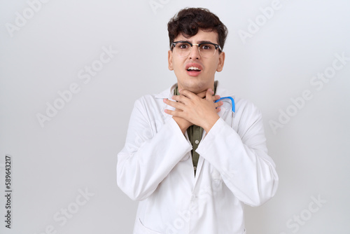Young non binary man wearing doctor uniform and stethoscope shouting and suffocate because painful strangle. health problem. asphyxiate and suicide concept.