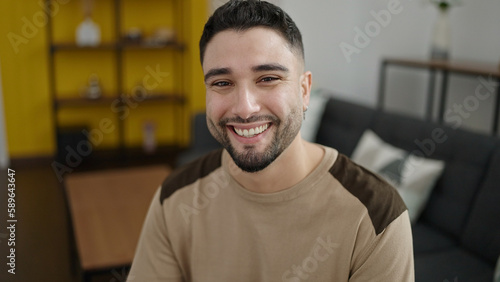 Young arab man smiling confident sitting on sofa at home