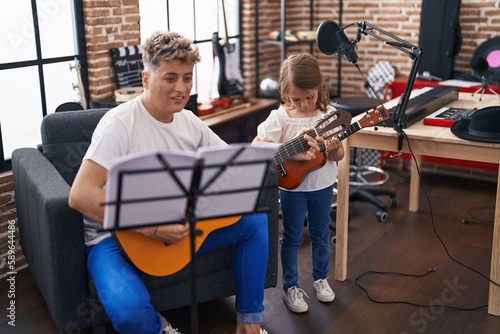 Father and daughter playing classical guitar and ukulele at music studio
