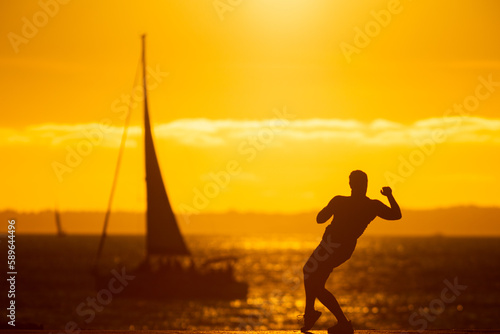 Fototapeta Naklejka Na Ścianę i Meble -  An inspired man dancing on the waterfront at sunset