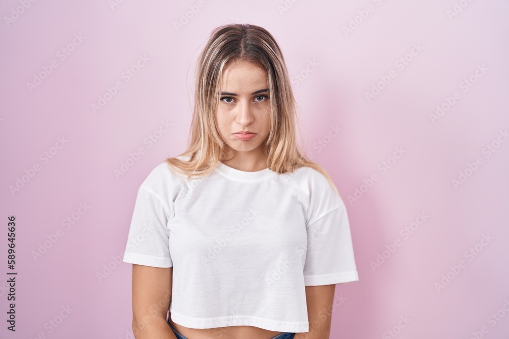 Young blonde woman standing over pink background depressed and worry for distress, crying angry and afraid. sad expression. Young blonde woman standing over pink background depressed and worry for distress, crying angry and afraid. sad expression.