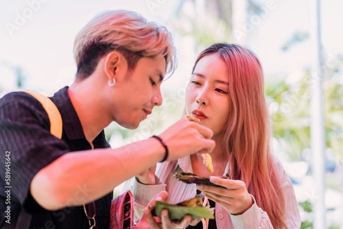 asian tourist couple eating local food. young teenage girl and boy tasting thailand northern local food while traveling. female and male lover trying tasting chiangmai traditional cuisine at location