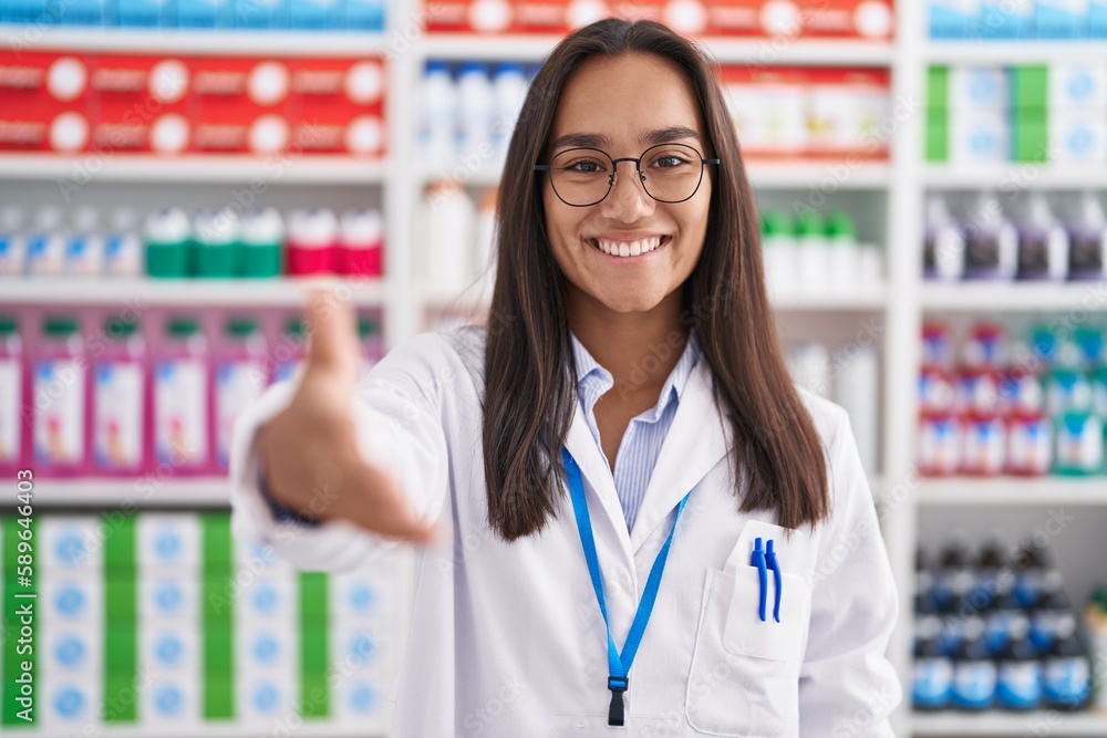 Young beautiful hispanic woman pharmacist smiling confident shake hand at pharmacy