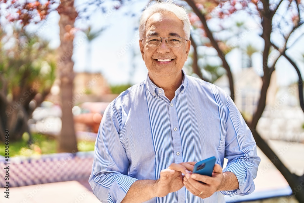 Fototapeta premium Senior man smiling confident using smartphone at park